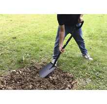 Een persoon graaft in de tuin met een spade.