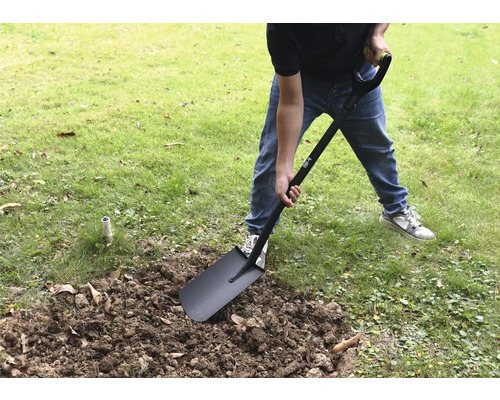 Een persoon graaft in de tuin met een spade.