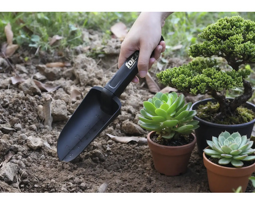 Tuinschep met markeringen in gebruik naast planten in potten.