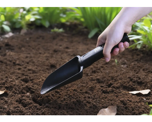 Iemand gebruikt een handgereedschap in de tuin.