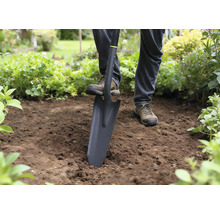 Persoon gebruikt een spade om in de tuin te graven.