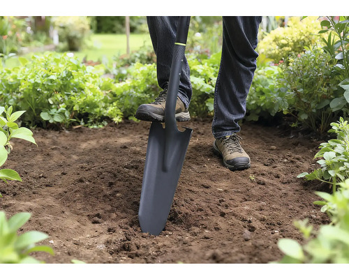 Persoon gebruikt een spade om in de tuin te graven.