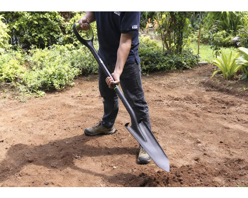 Man houdt spade in de tuin vast.