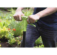 Persoon gebruikt een onkruidsteker in de tuin.