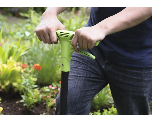 Persoon gebruikt een onkruidsteker in de tuin.