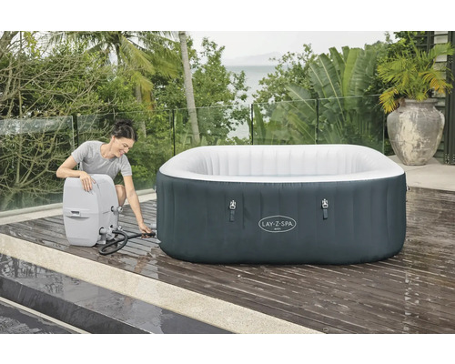Opblaasbare Lay-Z-Spa Ibiza whirlpool met filtersysteem op een terras, een vrouw sluit de slang aan