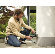 Man sluit buitenstopcontact aan op de muur van het huis