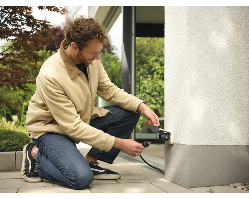 Man sluit buitenstopcontact aan op de muur van het huis