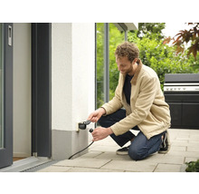 Man sluit stekker aan op stopcontact buiten