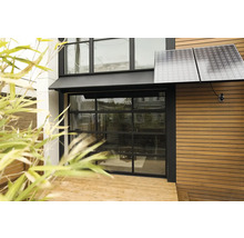 Buitenaanzicht van een huis met zonnepanelen en glazen garagedeur