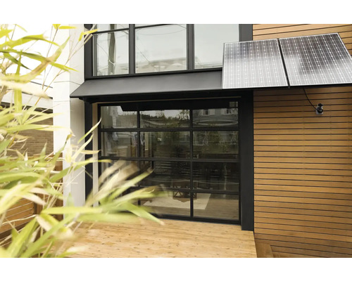 Buitenaanzicht van een huis met zonnepanelen en glazen garagedeur