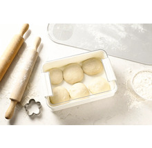 Deeg in vershouddoos naast deegroller, koekjesvorm en deegmat