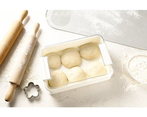 Deeg in vershouddoos naast deegroller, koekjesvorm en deegmat