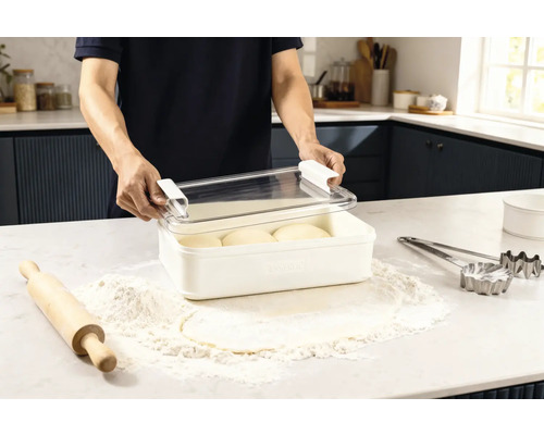 Scene in een keuken: een man opent een vershouddoos met deeg, omringd door bloem, een deegroller en uitsteekvormen.
