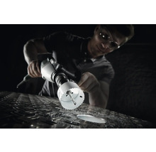 Een man boort met een gatenzaag een gat in een metalen oppervlak.