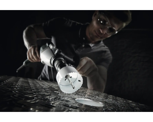 Een man boort met een gatenzaag een gat in een metalen oppervlak.