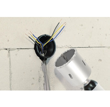 Muur met boorgat, elektrische kabels en een boorkroon.