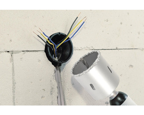 Muur met boorgat, elektrische kabels en een boorkroon.