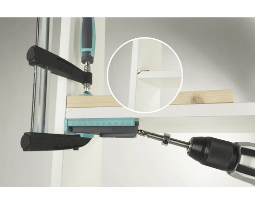 Een boormachine boort met behulp van een boormal een gat in een plank.