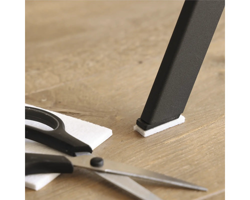 Stoelpoot met vilten glijder, vilten glijder en schaar op houten vloer