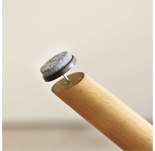 Viltglijder met spijker op een houten meubelpoot