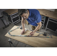 Een man gebruikt een profielmal om een vorm over te brengen op een houten plank.