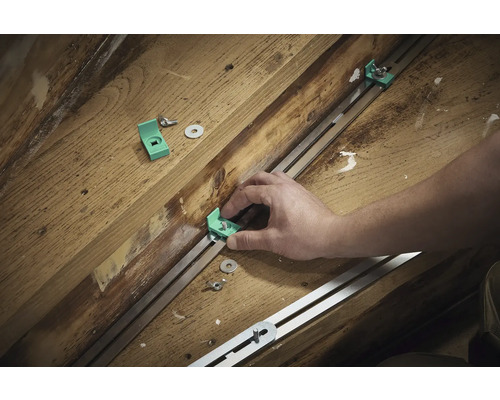 Montage van montagehoeken met schroeven en sluitringen op een metalen rail op een houten ondergrond