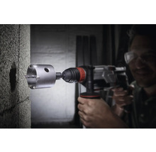 Man boort met een boormachine een gat in een muur.