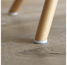 Detailweergave van een stoelpoot met vloerbeschermer op een houten vloer.