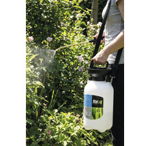 Een persoon gebruikt een for_q tuinspuit om planten te besproeien.