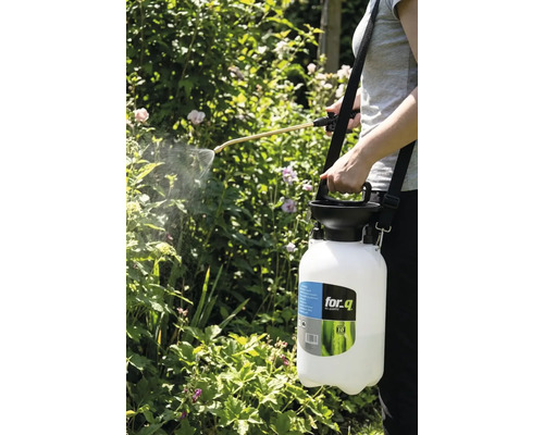 Een persoon gebruikt een for_q tuinspuit om planten te besproeien.