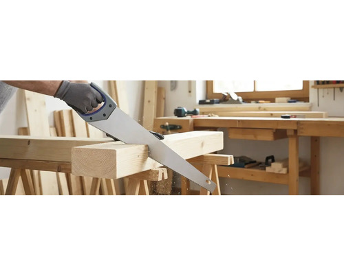 Een handzaag snijdt een stuk hout op een werkbank.