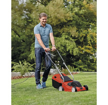 Een man maait het gazon met een elektrische grasmaaier.