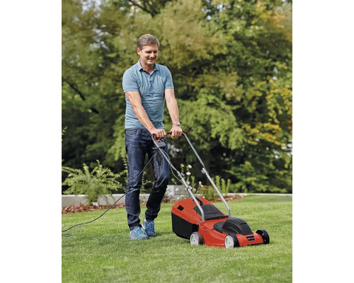 Een man maait het gazon met een elektrische grasmaaier.