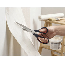 Een persoon snijdt behang met een schaar van het merk Rautner