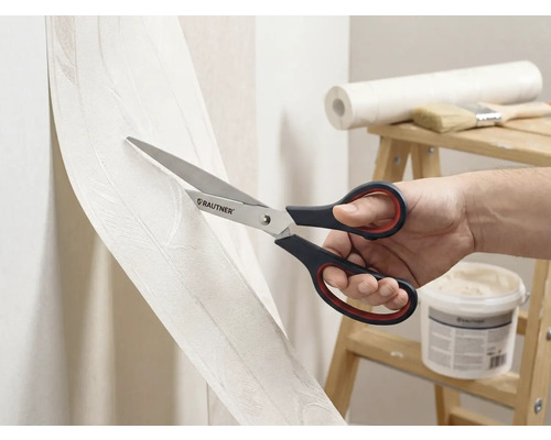 Een persoon snijdt behang met een schaar van het merk Rautner