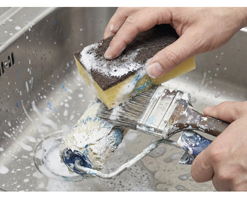 Reiniging van verfroller en kwast met een spons in de gootsteen.