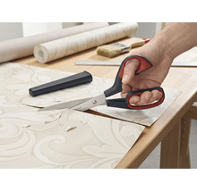 Behangschaar knipt behang op een tafel.