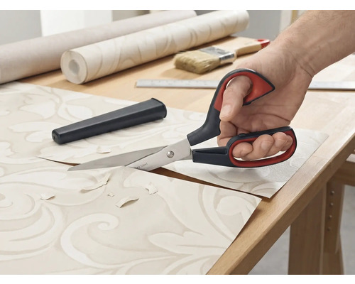 Behangschaar knipt behang op een tafel.