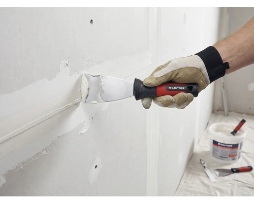 Ambachtsman plamuurt muur met plamuurmes en vulmiddel. Rautner Logo zichtbaar.