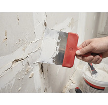 Ambachtsman plamuurt een muur met een plamuurmes