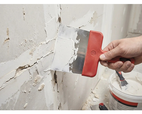 Ambachtsman plamuurt een muur met een plamuurmes