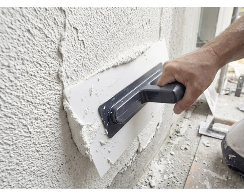 Vakman brengt gips aan op een muur met een pleisterspaan.