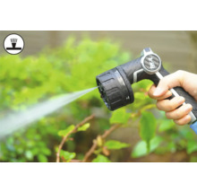 Hand houdt tuinslangspuitpistool vast tijdens het besproeien van planten