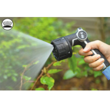 Een hand houdt een tuinspuit vast die water sproeit