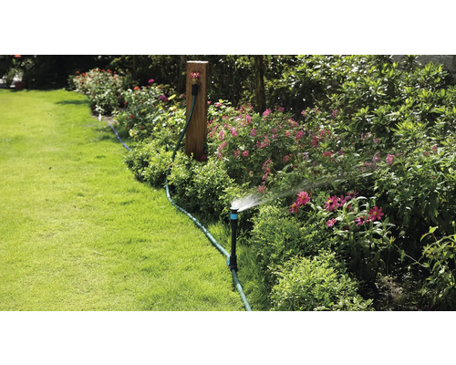 Tuinbewatering met gazonsproeier in een bloeiende tuin.