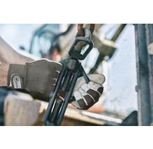 Close-up van handen met werkhandschoenen die een bankschroef bedienen