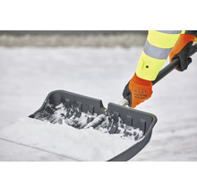 Persoon schept sneeuw met een sneeuwschuiver