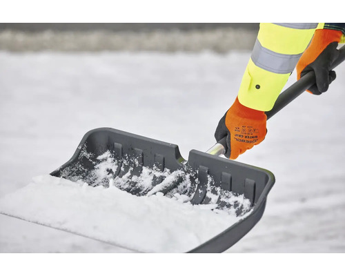 Persoon schept sneeuw met een sneeuwschuiver