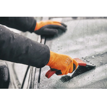 Persoon met handschoenen gebruikt een ijskrabber op een voorruit
